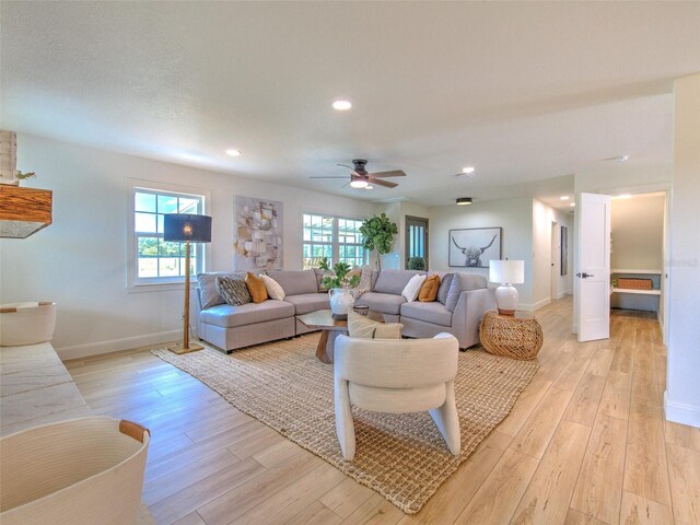 living room featuring light wood-type flooring, ceiling fan, and a healthy amount of sunlight