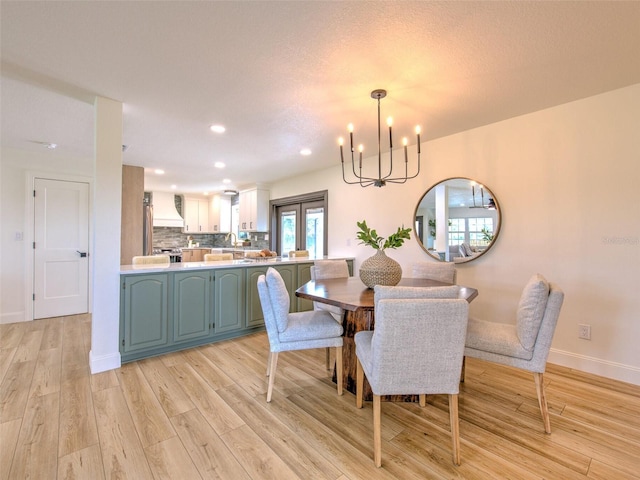 dining space with light wood-type flooring, an inviting chandelier, and a textured ceiling