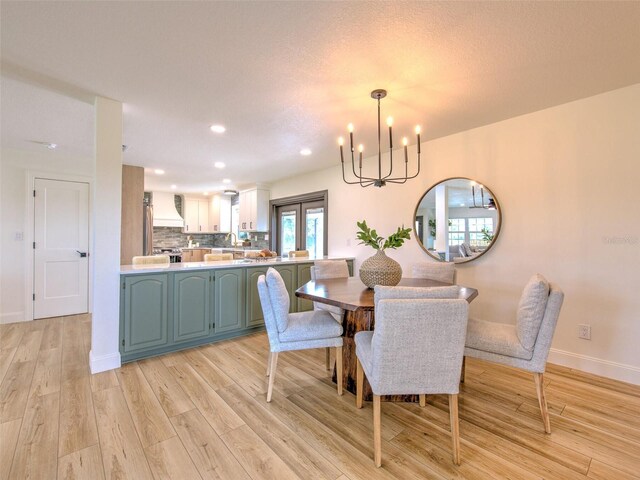 dining area with baseboards, recessed lighting, an inviting chandelier, and light wood-style floors