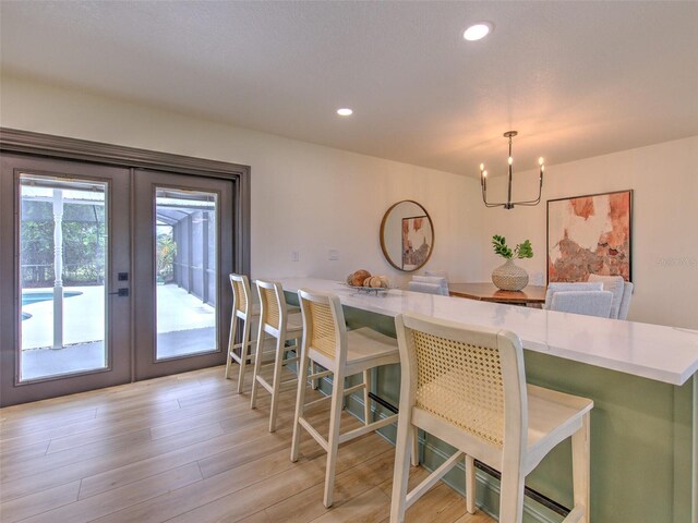 dining area with french doors, recessed lighting, an inviting chandelier, and light wood-type flooring