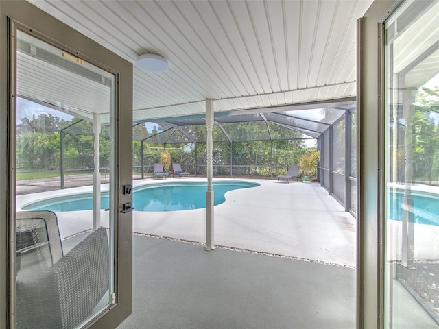 view of swimming pool featuring a patio area and glass enclosure