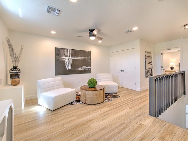 sitting room with light wood-type flooring, a textured ceiling, and ceiling fan