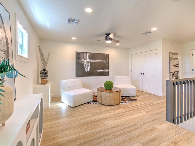 living room featuring a textured ceiling, ceiling fan, and light wood-type flooring