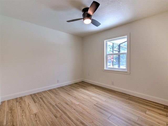 unfurnished room featuring baseboards, a textured ceiling, a ceiling fan, and light wood finished floors