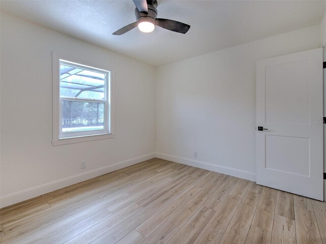 spare room with baseboards, light wood-type flooring, and ceiling fan
