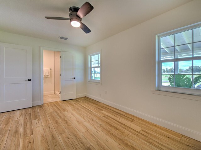 unfurnished bedroom with light wood-style flooring, baseboards, connected bathroom, visible vents, and a ceiling fan