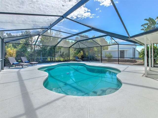 outdoor pool featuring glass enclosure and a patio area