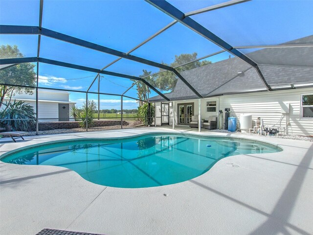 outdoor pool with glass enclosure, french doors, and a patio area
