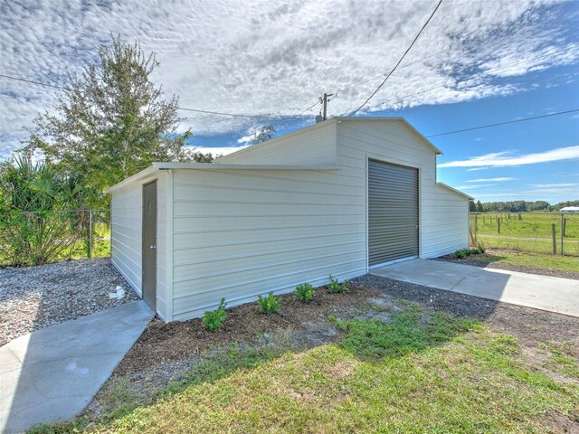 detached garage featuring driveway and fence