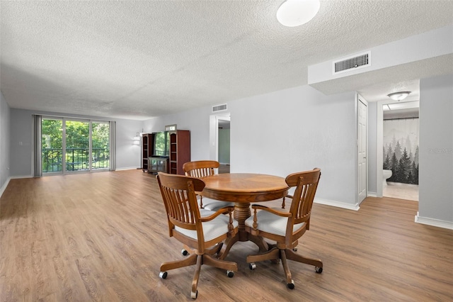 dining room featuring a textured ceiling and light hardwood / wood-style flooring