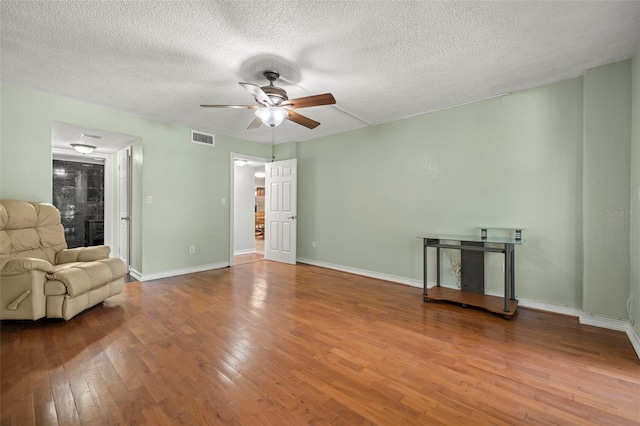 unfurnished living room featuring wood-type flooring, a textured ceiling, and ceiling fan