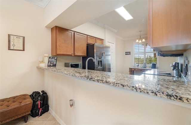 kitchen with tile patterned flooring, stainless steel fridge, a peninsula, and crown molding