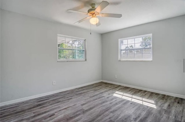 unfurnished room with ceiling fan, a wealth of natural light, and dark hardwood / wood-style flooring