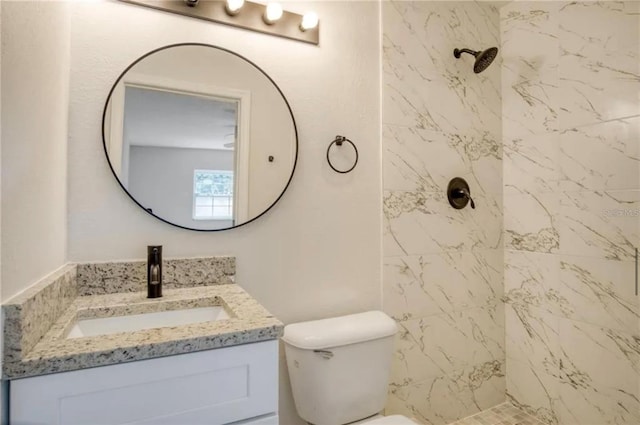 bathroom featuring toilet, a tile shower, and vanity