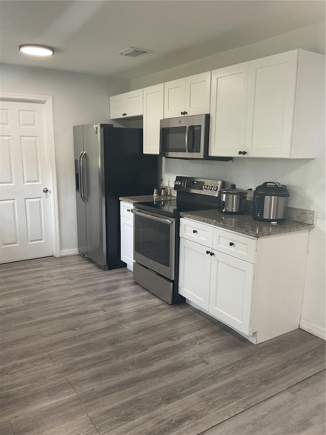 kitchen featuring dark hardwood / wood-style flooring, stainless steel appliances, and white cabinetry