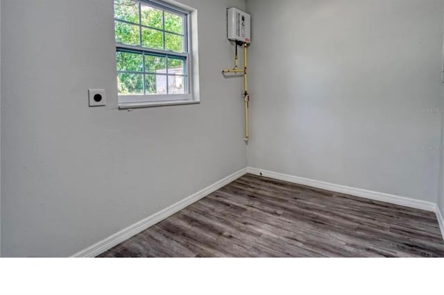 empty room with dark hardwood / wood-style flooring and water heater