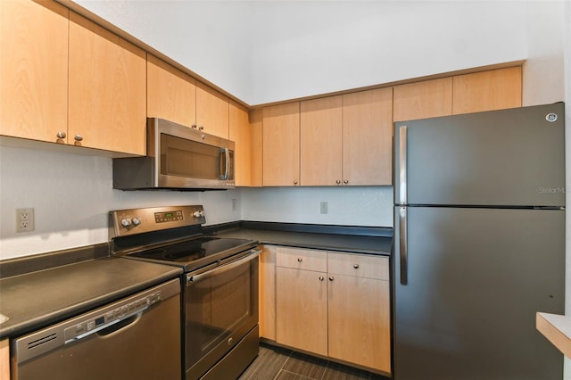 kitchen with appliances with stainless steel finishes, dark countertops, and light brown cabinets