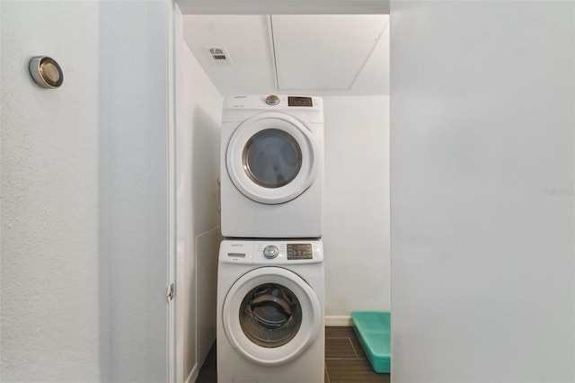 washroom featuring dark hardwood / wood-style floors and stacked washer / dryer