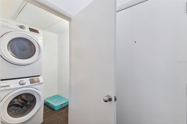 clothes washing area featuring stacked washer / drying machine and dark tile patterned floors