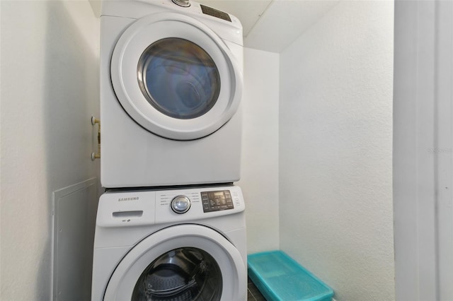 laundry area featuring stacked washer and dryer and a textured wall