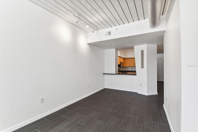 unfurnished living room featuring rail lighting, baseboards, wood tiled floor, and visible vents