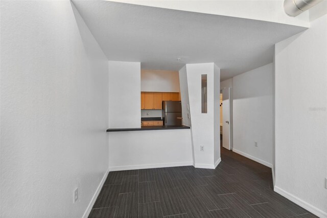 unfurnished living room featuring baseboards and wood tiled floor