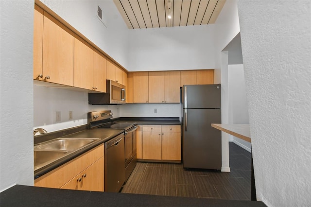 kitchen featuring stainless steel appliances, sink, dark tile patterned floors, and light brown cabinetry