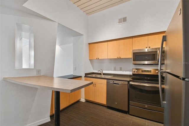 kitchen with light brown cabinetry, sink, appliances with stainless steel finishes, and kitchen peninsula