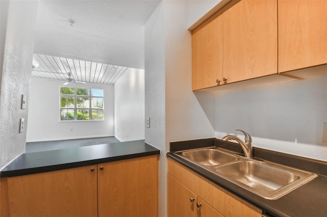 kitchen with a textured wall, dark countertops, and a sink