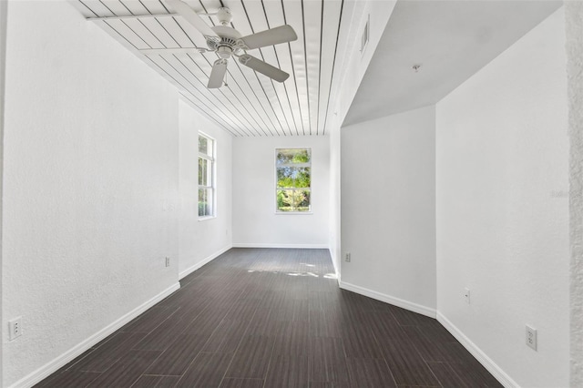 spare room with a ceiling fan, visible vents, baseboards, and wood finished floors