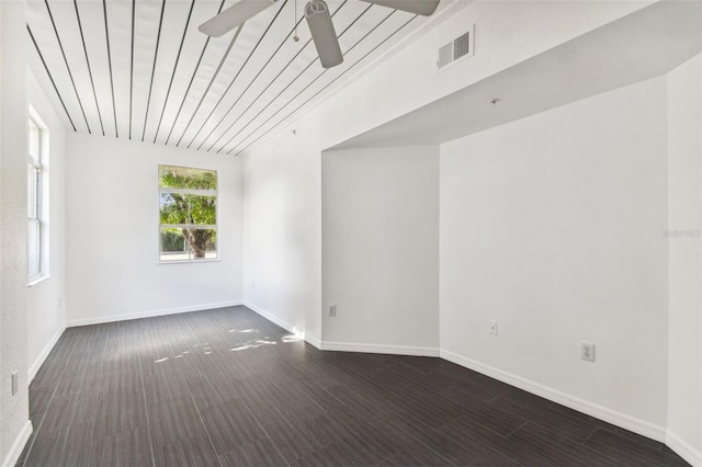 spare room featuring ceiling fan, dark wood-style flooring, visible vents, and baseboards