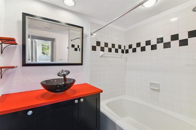 full bathroom with bathtub / shower combination, a textured wall, and vanity