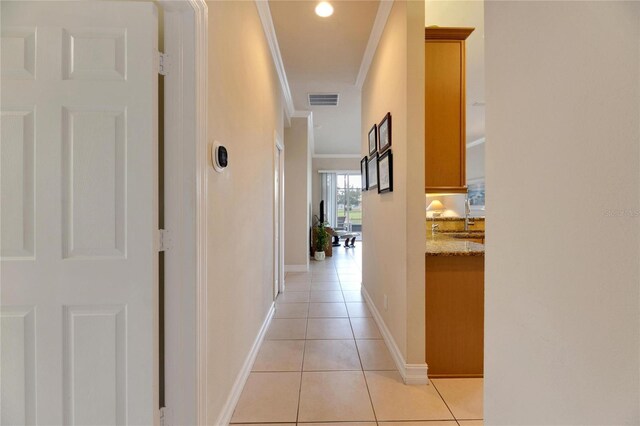 hall featuring light tile patterned floors, ornamental molding, and sink