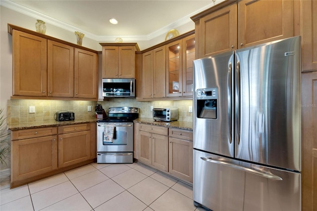 kitchen featuring light stone countertops, decorative backsplash, stainless steel appliances, and crown molding