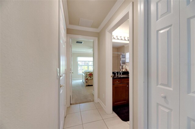 hallway featuring light tile patterned floors, crown molding, and sink