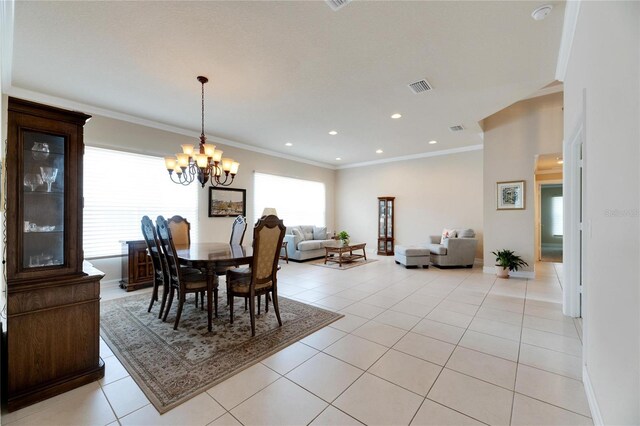 tiled dining space featuring a healthy amount of sunlight, crown molding, and an inviting chandelier