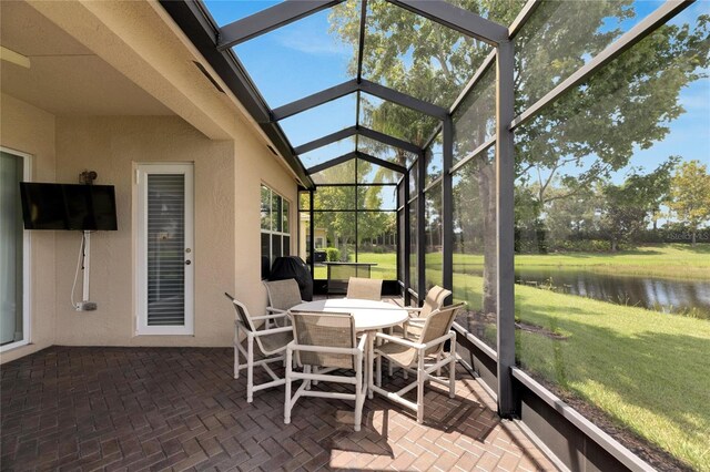 sunroom featuring a water view and lofted ceiling