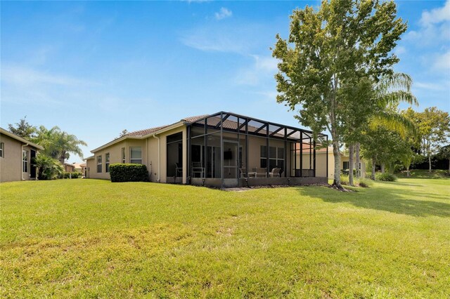 back of house featuring glass enclosure and a yard