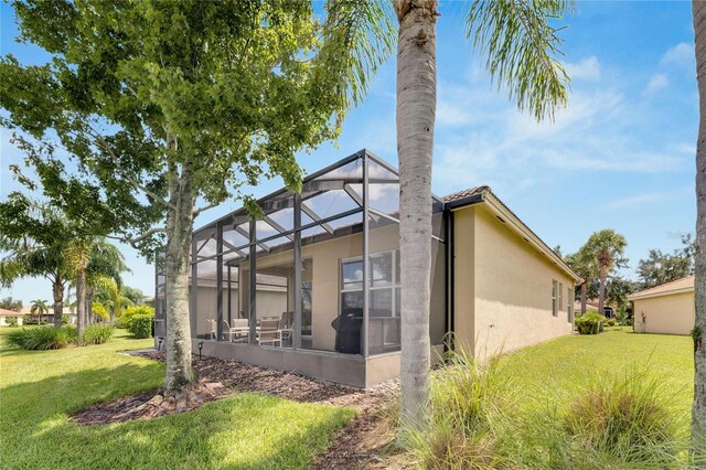 view of side of property with a lanai and a lawn