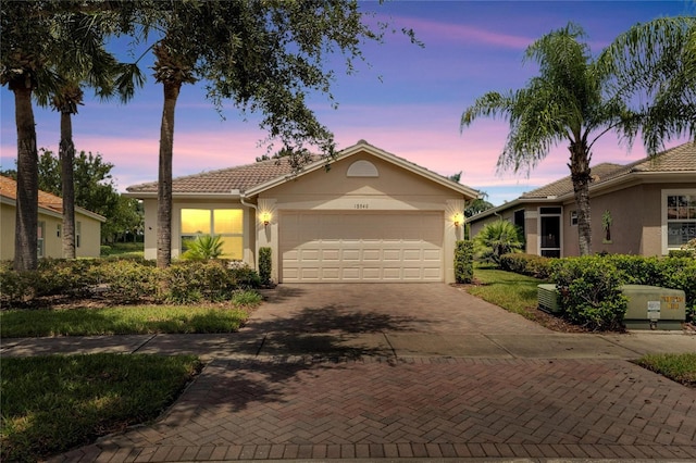 single story home featuring a tile roof, decorative driveway, an attached garage, and stucco siding