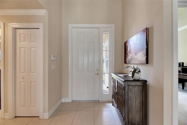 foyer entrance with light tile patterned floors and ornamental molding