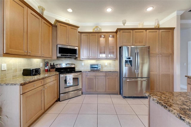 kitchen featuring backsplash, light tile patterned floors, ornamental molding, appliances with stainless steel finishes, and light stone counters