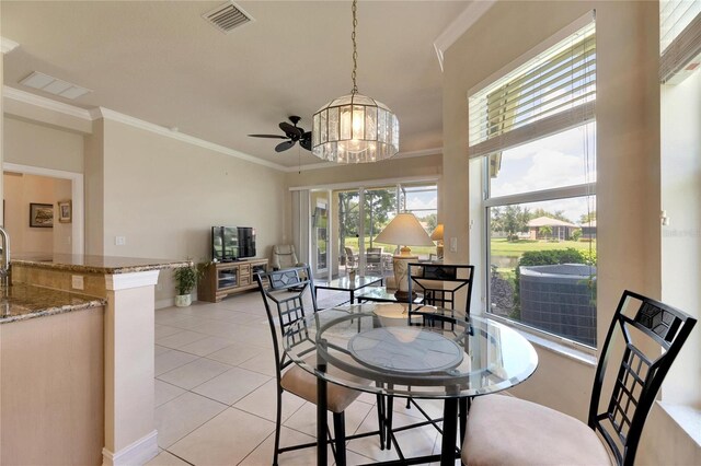 tiled dining space with ceiling fan with notable chandelier and ornamental molding