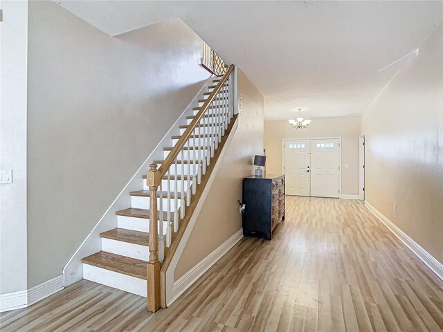 foyer entrance with light hardwood / wood-style floors and a notable chandelier