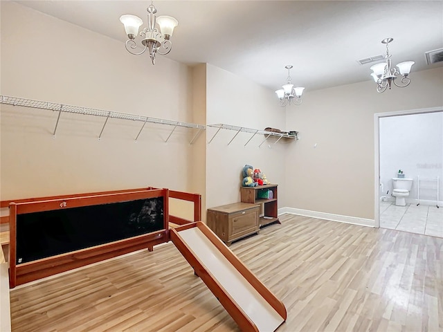 walk in closet featuring a chandelier and light hardwood / wood-style floors