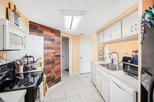 kitchen with tasteful backsplash, light tile patterned floors, black appliances, sink, and white cabinets