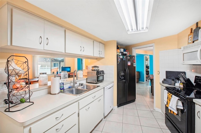 kitchen featuring white cabinets, black appliances, sink, decorative backsplash, and light tile patterned flooring