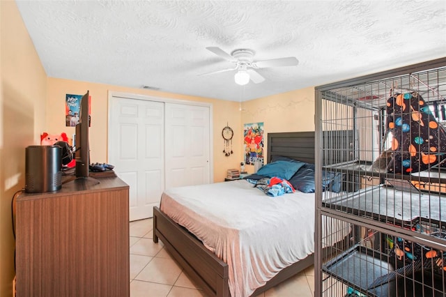 bedroom with a closet, ceiling fan, light tile patterned floors, and a textured ceiling