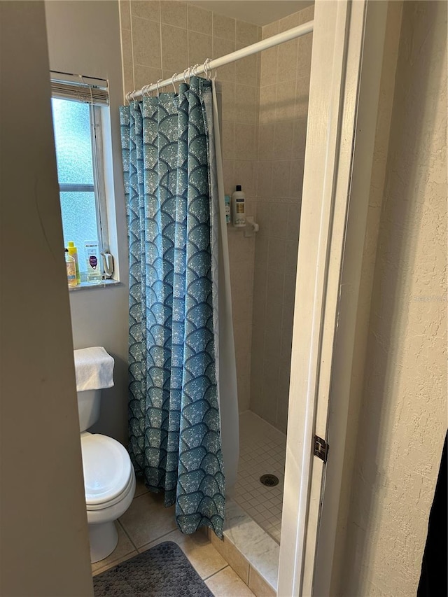 bathroom featuring toilet, a shower with curtain, and tile patterned floors