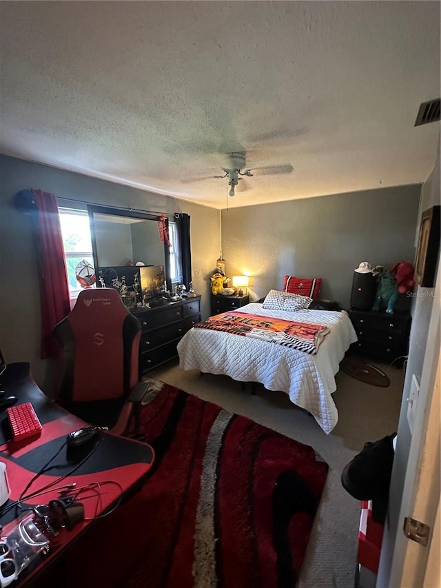 carpeted bedroom with ceiling fan and a textured ceiling